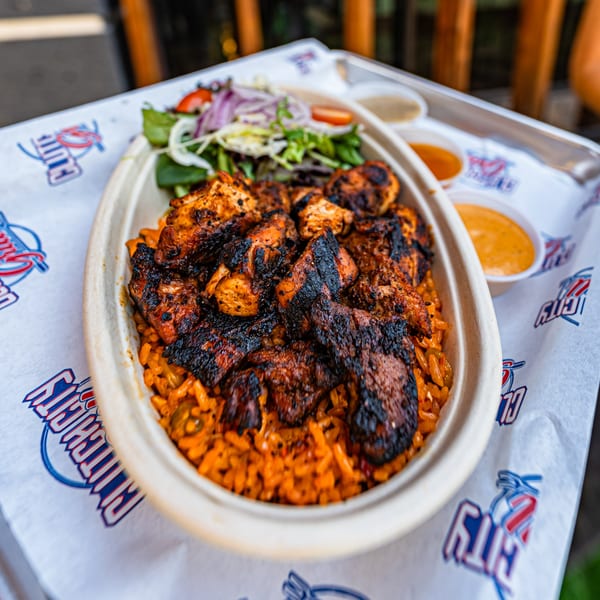 Clutch City Grill's grilled chicken and rice bowl with a side salad and dipping sauces.