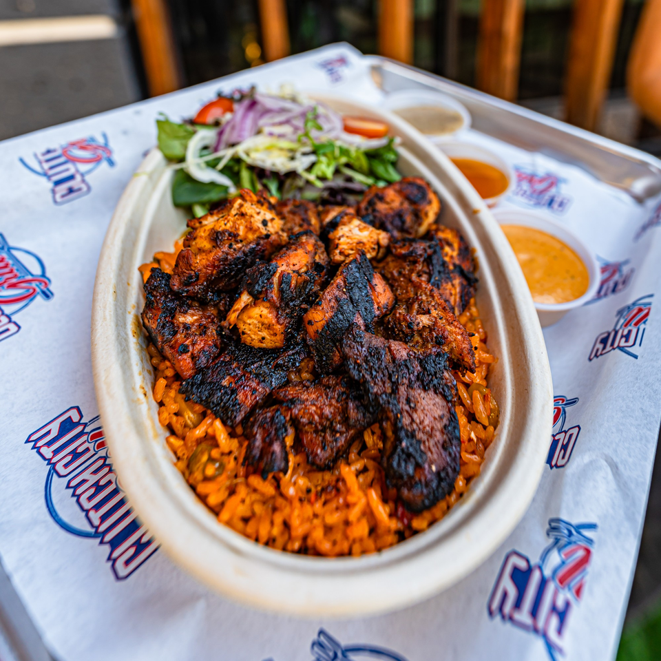 Clutch City Grill's grilled chicken and rice bowl with a side salad and dipping sauces.