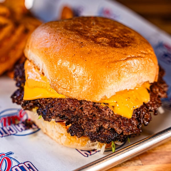 Close-up of a Clutch City Grill cheeseburger with two patties, melted cheese, and a toasted bun.