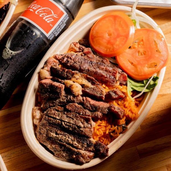 Clutch City Grill's steak and rice dish with tomato slices and a Coca-Cola bottle.